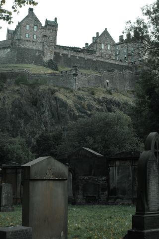 View of an old cemetery with old building on a hill in the background