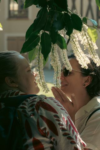 Two women smelling the scent of a white flower