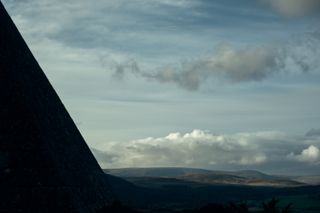A side of a pyramid in the foreground and wide valley in the background
