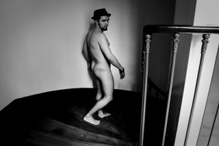 A nude man going down a staircase