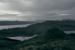 Landscape view of a series of mountains and lochs in Scotland on a cloudy day