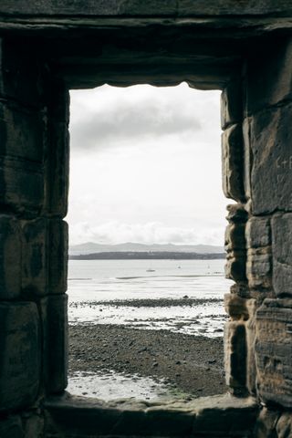 View through a stone window on shores with Edinburgh in the background