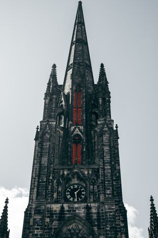 Bell tower of a church made of black stone and shutters painted in red