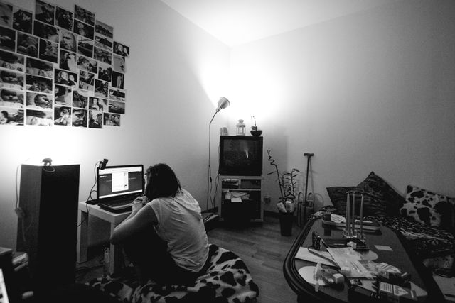 Living room of a woman, she is sitting on the ground and watching for something on her computer
