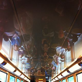 View of a crowded train from the reflection of the ceiling