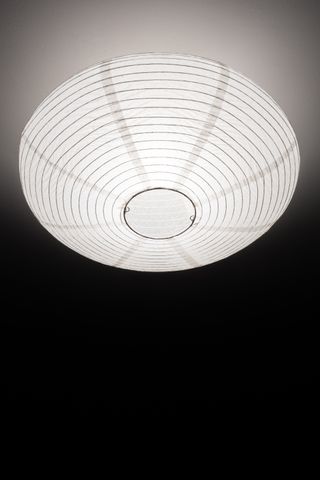 Round lampshade with the light on on a white ceiling