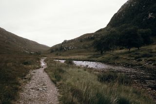 A rocky path along a river going through a small valley